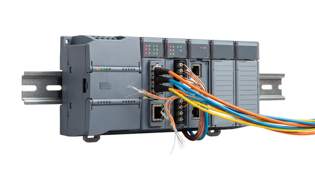 Industrial PLC automation module, programmable logic controller terminal unit mounted on DIN rail with multicolored wiring bundle. Factory industrial automation control on transparent background.