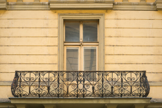 sanierungsbed&uuml;rftige Fassade eines Wohnhauses aus der Gr&uuml;nderzeit mit einem schmiedeeisernen Balkon in der Neustadt von Prag