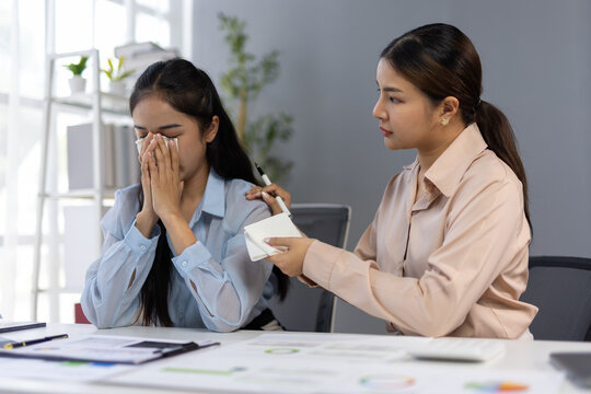 Manager comforting crying employee in the office.