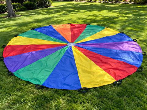 Ultra Realistic Large Colorful Outdoor Play Parachute Spread on Green Grass Premium Group Recreation Concept