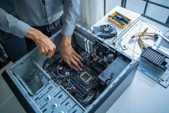Asian IT engineer man fixing mainboard in pc case on working table