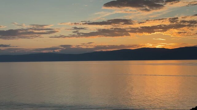 Time-lapse video of beautiful landscape of Baikal Lake at sunset. View from Olkhon Island coast to golden water of Small Sea in evening. Seagulls flying over the water. Natureal background