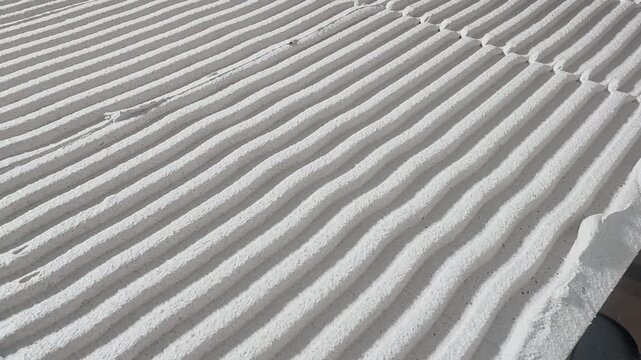 Close-up of tile adhesive combed into uniform parallel ridges, showing precise surface preparation for strong ceramic bonding during professional indoor renovation.