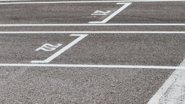 Close view of a go-kart track start grid with white lane markings and numbered positions on asphalt beside trimmed grass, suitable for racing, training and motorsport themes.