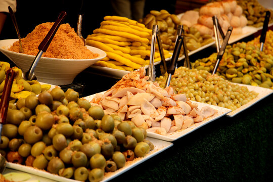 Assorted Thai pickled and preserved fruits displayed in large trays at a night market.