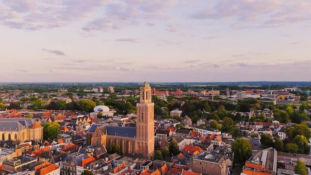 Golden-hour drone view over Zwolle&rsquo;s historic center, with the Peperbus and Basilica of Our Lady rising above dense red rooftops and green neighborhoods in the Netherlands.