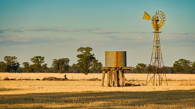 Rustic farm windmill beside corrugated water tank