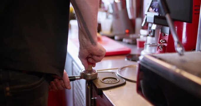 Making caffeine drink. Tamping coffee. Male barista hand pressing grinded beans powder in metal horn. Professional restaurant appliance.