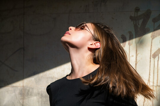 Thoughtful woman with serious facial expression. Thoughtful model in dramatic light and shadow. Fashion portrait of thoughtful brunette outdoors. Direct gaze with thoughtful female emotion.