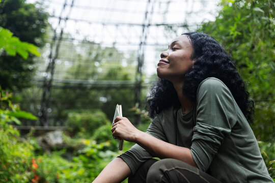 Relaxed Woman with Eyes Closed Enjoying a Peaceful Moment in a Botanical Garden