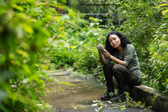 Woman Taking Notes and Learning About Nature in a Lush Botanical Garden
