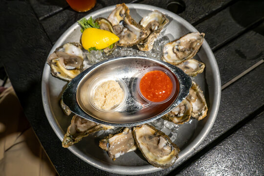 Solomons, Maryland USA A serving of a dozen raw oysters in their shell on ice with horseradish and hot sauce.