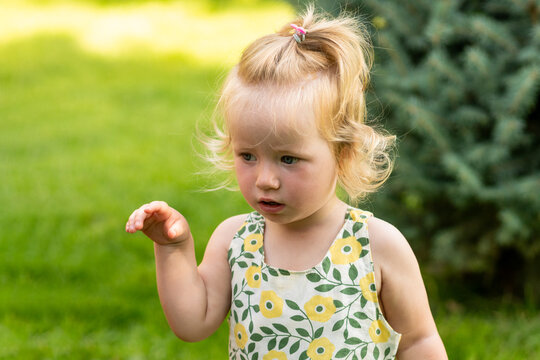 Serious Toddler Girl Raising One Hand Outdoors