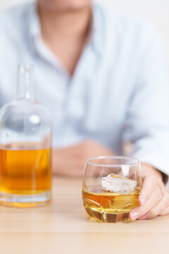 man with glass of whiskey on table, suffering from alcohol addiction and alcoholism concept. depicting emotional distress, depression, substance abuse problem, unhealthy lifestyle and mental health