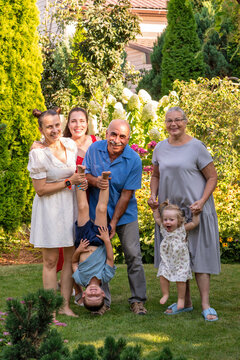 Extended Family Playing With Grandchildren in Sunny Garden