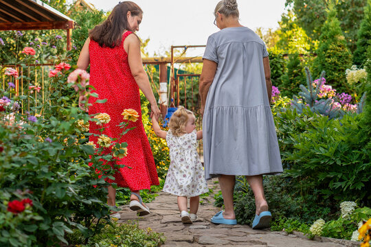Three Generations Walking Hand In Hand Through Flower Garden