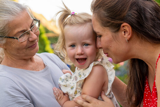 Happy Girl With Mother And Grandmother In Garden
