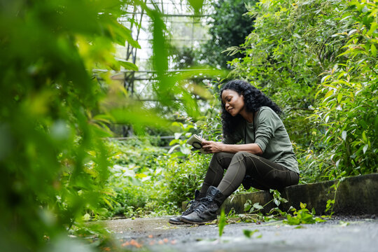 Woman with Notebook Enjoying Nature Inside a Lush Botanical Dome