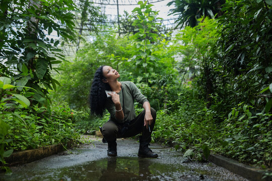 Environmental Education and Nature Exploration: Woman Observing Tropical Plants Inside a Botanical Dome