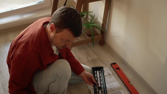 Concentrated man carefully studying the instructions to assemble a new tv wall mount. Handyman working on a diy home improvement project, installing a bracket for a flat screen television