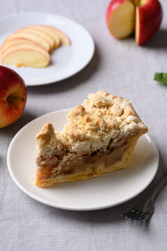 Apple crumble pie slice on white plate and fresh apple fruit, autumn dessert for Thanksgiving and fall season