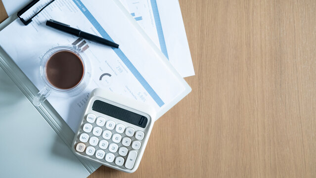Calculator, coffee and financial reports on office desk with large copy space. Business budgeting, accounting, investment planning and financial analysis concept.