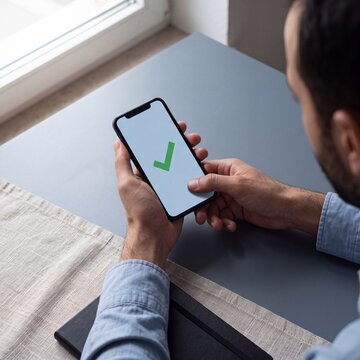 Gr&uuml;nes H&auml;kchen auf Smartphone-Bildschirm als Best&auml;tigung