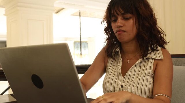 Young Indian Gen Z woman working remotely on laptop in a public lobby, browsing online job opportunities and learning artificial intelligence, career development, remote work, technology