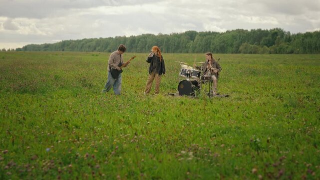 Caucasian indie rock band playing musical instruments and singing in green field with camera zooming in. Perfect for music festival promos, youth culture campaigns, and streaming ads
