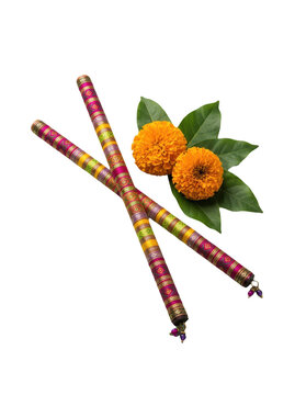 Two colorful decorated dandiya sticks with orange marigold flowers for navratri festival celebration