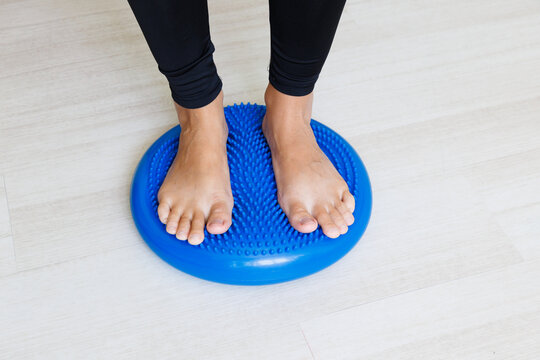 Both feet stand on a massage balance cushion during preventive exercise for arch support, ankle stabilization, posture control and coordinated weight distribution.