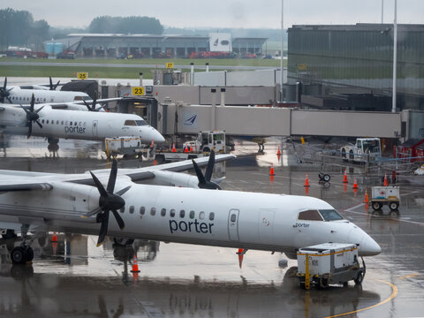 Ottawa, ON, Canada - Sept 13, 2026: Porter Airlines turboprop airplanes parked at airport jet bridges on a wet, rainy tarmac.