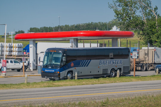 Calgary, AB, Canada - Sept 13, 2026: A Brewster charter bus parked at a gas station service area under a bright red canopy on a sunny day.