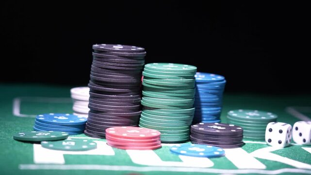 Colorful poker chip stacks rise on green felt. Two dice display six and five. Dark backdrop emphasizes gambling setup. Ideal for casino ads or betting scenes
