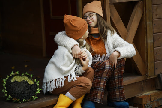Cozy Autumn Moment: Two Children in Warm Knitwear Sitting on a Porch