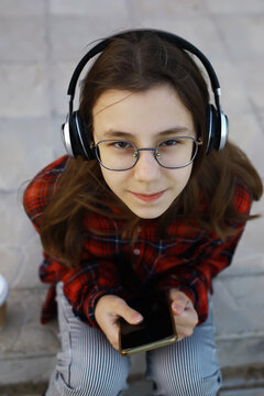 Youthful Focus: Teen Listening to Music with Headphones and Smartphone Outdoors