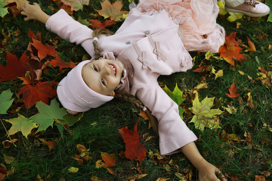 Joyful Child Playing in Colorful Autumn Leaves in Stylish Pink Outfit