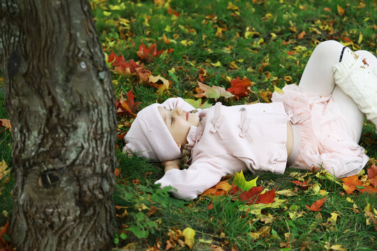 Child Relaxing on Autumn Leaves in Cozy Pink Outfit