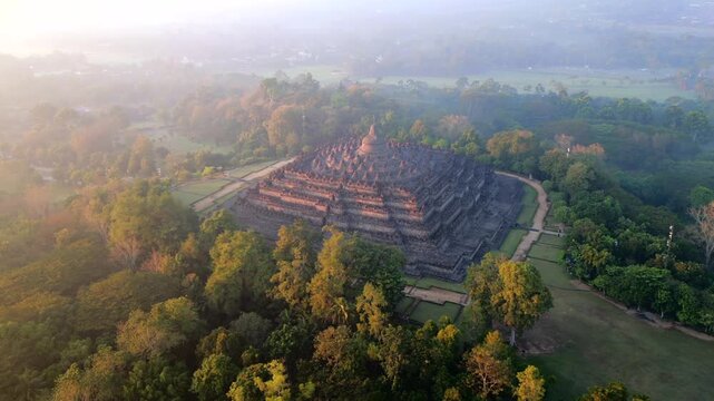 Aerial view of Borobudur Temple at sunrise in Central Java, Indonesia. Ancient Buddhist monument covered in mystical morning mist. UNESCO World Heritage Site, culture, history, and travel themes.