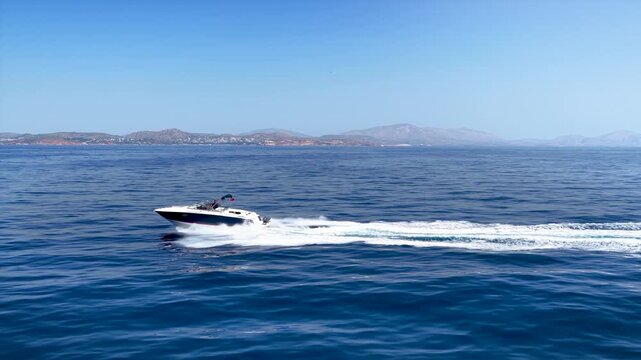 Aaerial view of a motorboat cruising with high speed over the ocean and leaving a trail of surf and waves behind