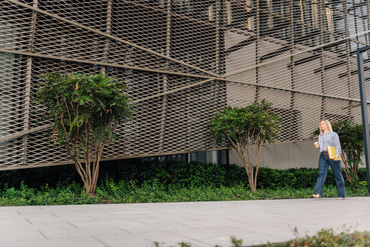 Businesswoman walking in urban setting holding coffee