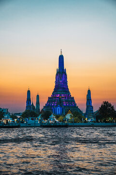 Wat arun temple illuminated at sunset by chao phraya river