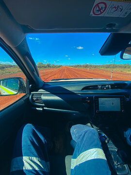 Driver traveling remote red dirt road in outback