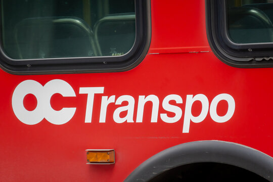 Ottawa, ON, Canada - Sept 13, 2026: Close-up of white OC Transpo logo printed on the red side exterior of a public city bus.