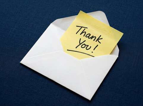 Yellow note with Thank You text in open envelope on dark blue fabric suitable for customer service symbolizing client gratitude and appreciation