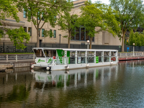 Ottawa, ON, Canada - Sept 13, 2026: An EKEAU electric passenger tour boat floats along the Rideau Canal near historic buildings.