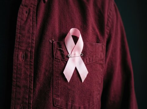 Pink ribbon pinned on a maroon shirt pocket ideal for medical campaign media symbolizing breast cancer awareness support and hope