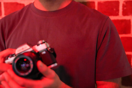 Person holding vintage film camera in red light