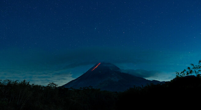 Mount merapi volcano erupting under starry night sky