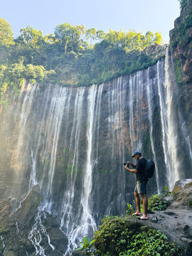 Man photographing tumpak sewu waterfall in indonesia